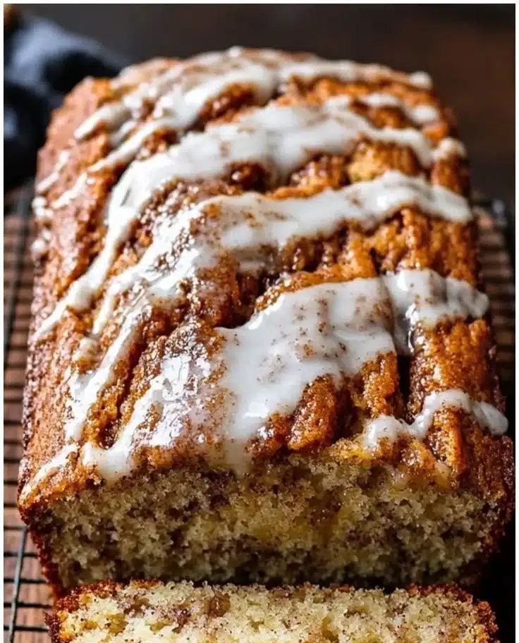 Freshly baked cinnamon swirl banana bread loaf on a wooden table.