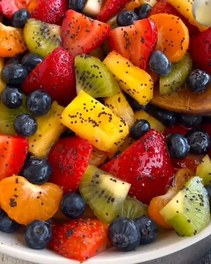 Vibrant fresh fruit salad with honey lime poppy seed dressing on a platter