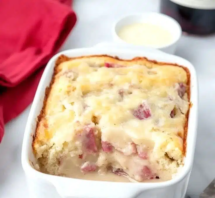 Slices of Moist Rhubarb Cake topped with creamy butter sauce on a white plate