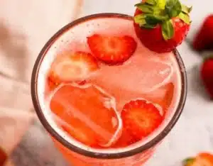 Glass of strawberry soda with bubbles and fresh strawberries