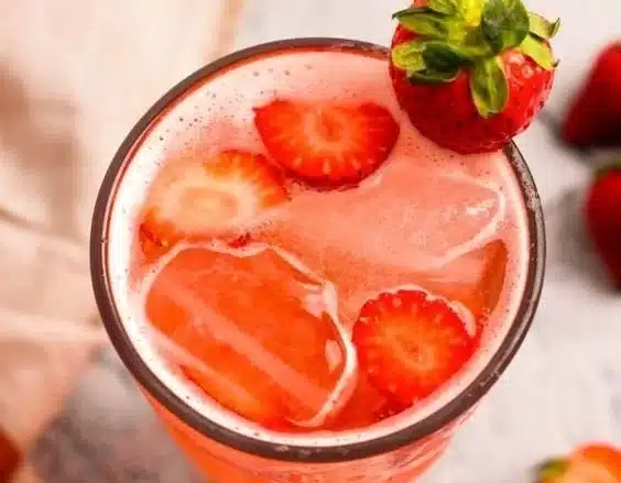 Glass of strawberry soda with bubbles and fresh strawberries
