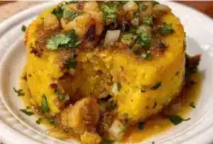 A plate of traditional Puerto Rican Mofongo garnished with garlic and pork cracklings.