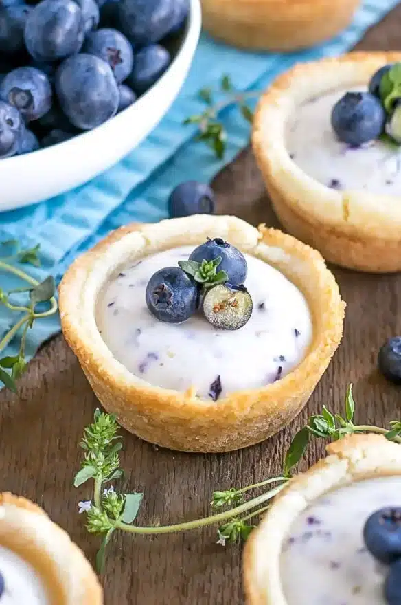 Blueberry Cheesecake Cookie Cups topped with fresh blueberries and cream cheese frosting