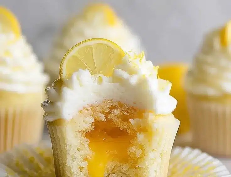 Delicious lemon stuffed cupcakes topped with frosting and lemon zest.