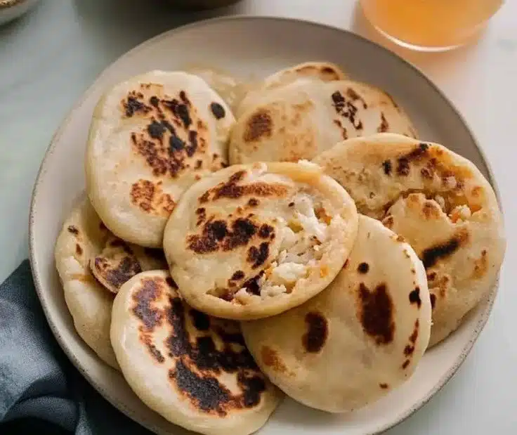 Homemade pupusas with a side of pickled cabbage on a rustic wooden table.