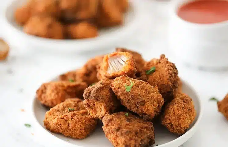 Vegan spicy chicken fried jackfruit garnished with herbs and spices.