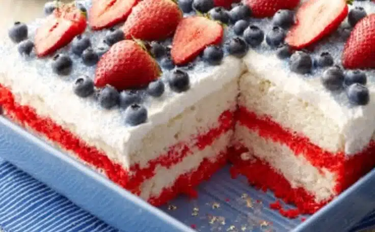 Delicious 4th of July Poke Cake topped with whipped cream and berries