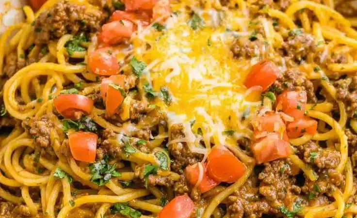 A serving of Taco Spaghetti topped with cheese and cilantro on a plate