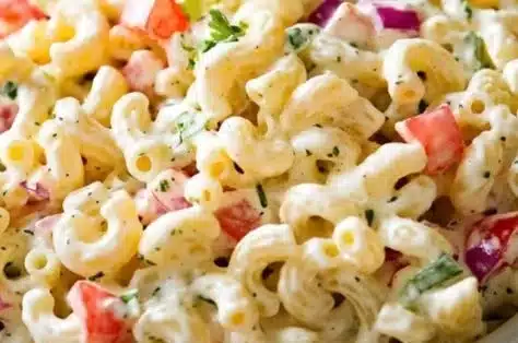 Creamy homemade macaroni salad in a bowl garnished with herbs