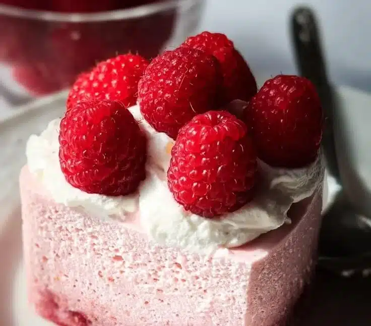 Delicious raspberry mousse dessert topped with fresh raspberries