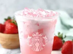 Delicious Starbucks copycat pink drink in a glass with berries and coconut milk