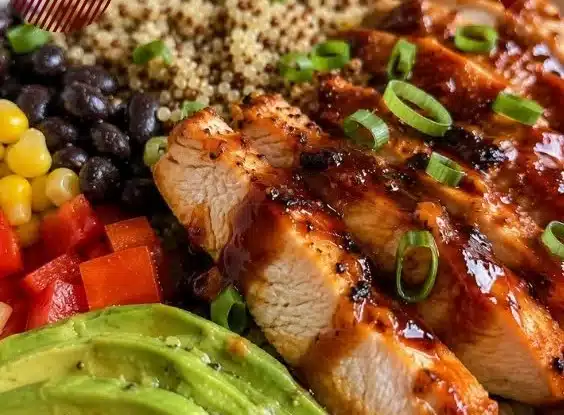 BBQ chicken quinoa bowl garnished with fresh vegetables and herbs