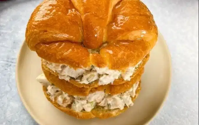 Delicious chicken salad sandwich served with fresh vegetables and herbs